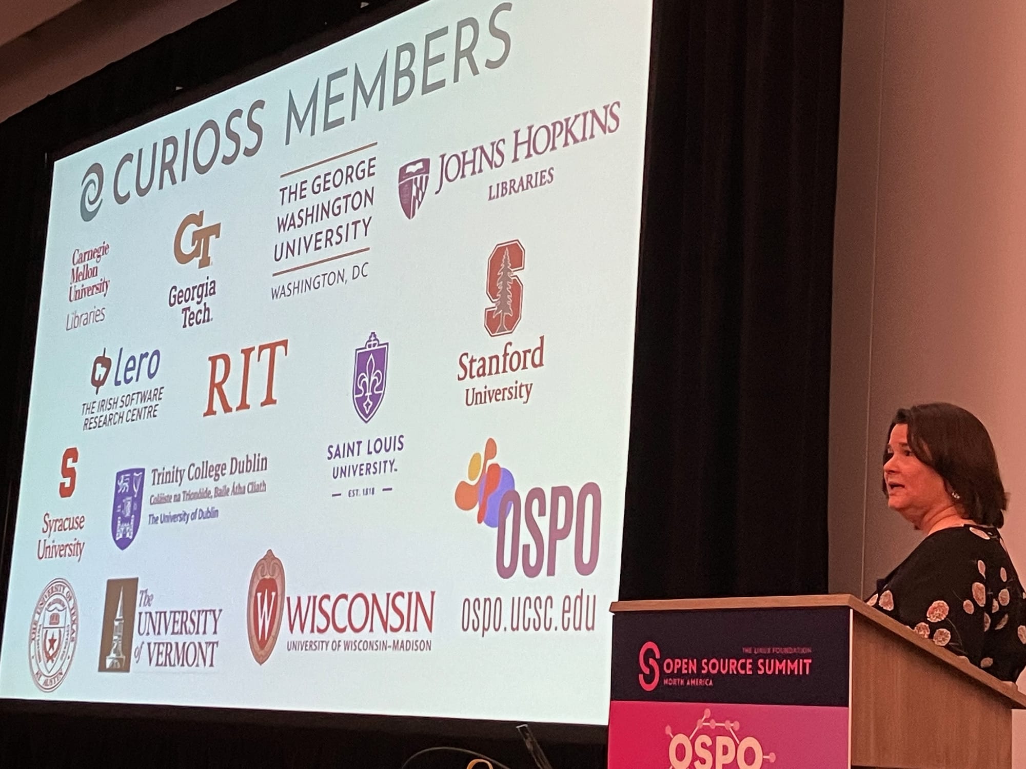 Stephanie Lieggie from UC Santa Cruz presenting a slide with the logos of universities participating in the Curioss community.